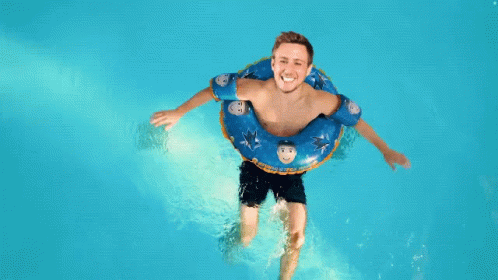 Man Floating In Pool With Blue Shark Tube GIF