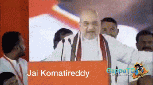 Man Giving Speech in Front of Jai Komatreddy Sign
