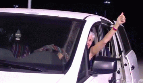 Man Giving Thumbs Up Driving White Car