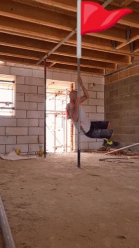Man Hanging Upside Down on Pole With Red Flag