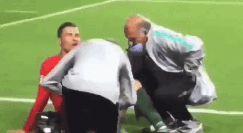 Man Helping Soccer Player Lying on Field