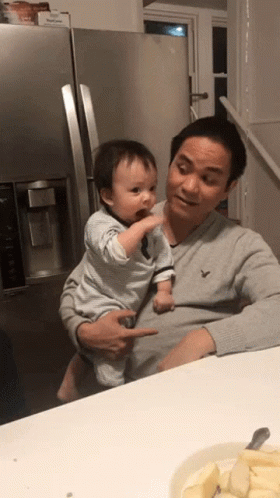 Man Holding Baby in Front of Fridge