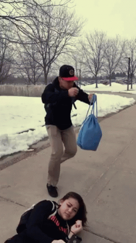 Man Holding Blue Bag While Woman Lays On Ground GIF