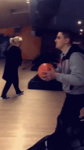 Man Holding Bowling Ball Woman Looking On