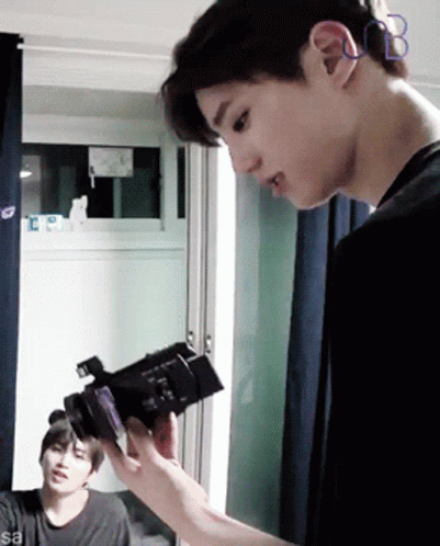 Man Holding Camera In Front Of Window With Letter B On Ear GIF