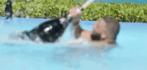 Man Holding Champagne Bottle in Pool