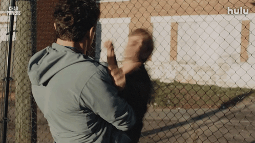 Man Holding Child in Front of Chad Powers Fence