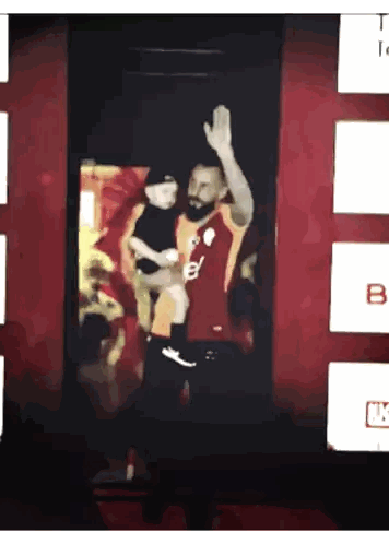 Man Holding Child in Front of Sign B