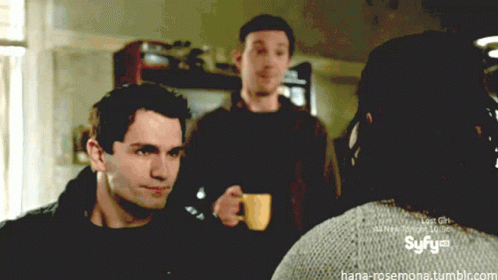 Man Holding Coffee In Front Of Syfy Logo GIF
