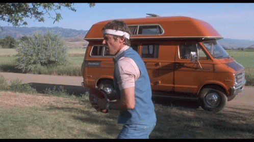 Man Holding Football Beside Orange Van RV