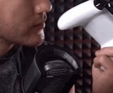 Man Holding Game Controller Talking Into Microphone