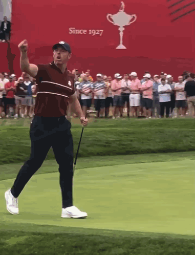 Man Holding Golf Club in Front of Since 1927 Sign