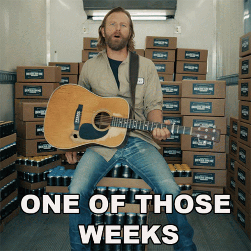 Man Holding Guitar in Front of Boxes