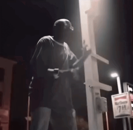 Man Holding Gun At 7 Eleven Sign Night GIF