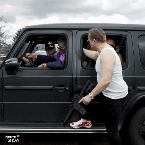 Man Holding Gun Next to Car Saying Heute Show