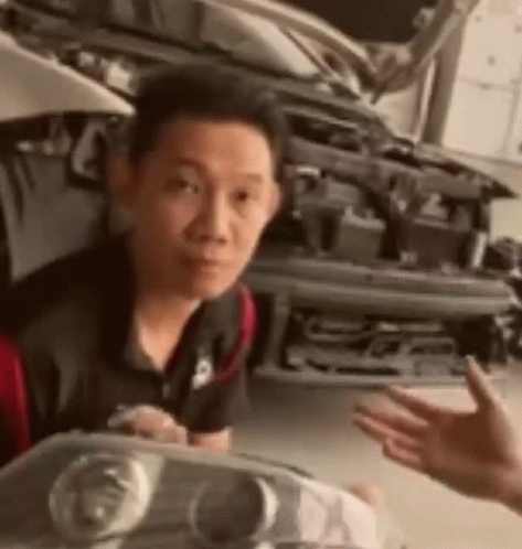 Man Holding Headlight In Front Of Car GIF