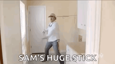 Man Holding Huge Stick In Kitchen GIF