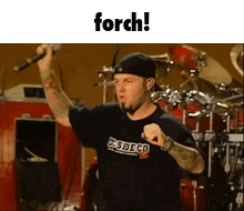 Man Holding Microphone at Drum Set Saying Forch