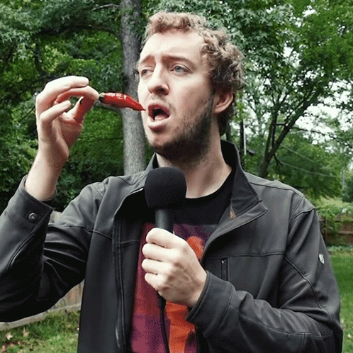Man Holding Microphone Eating Red Pepper