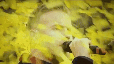 Man Holding Microphone In Field Of Yellow Papers GIF