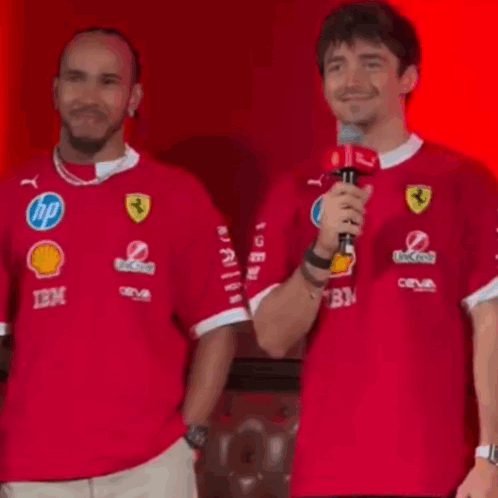Man Holding Microphone Next to Man in Red Shirt