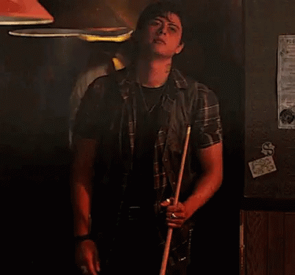 Man Holding Pool Cue in Dark Room