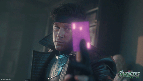 Man Holding Purple Object In Front Of Avengers Poster GIF