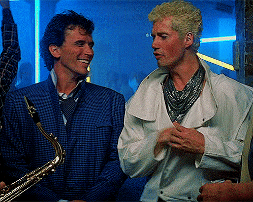 Man Holding Saxophone Talking to Man