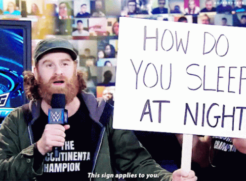 Man Holding Sign How Do You Sleep at Night