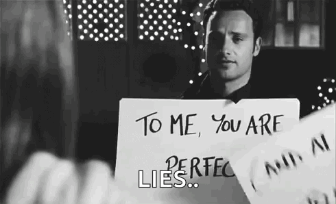 Man Holding Sign That Says You Are Perfect Lies