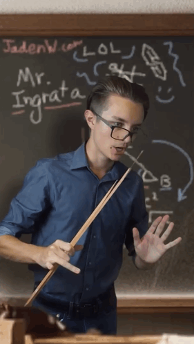 Man Holding Stick in Front of Blackboard With Mr. Ingrata