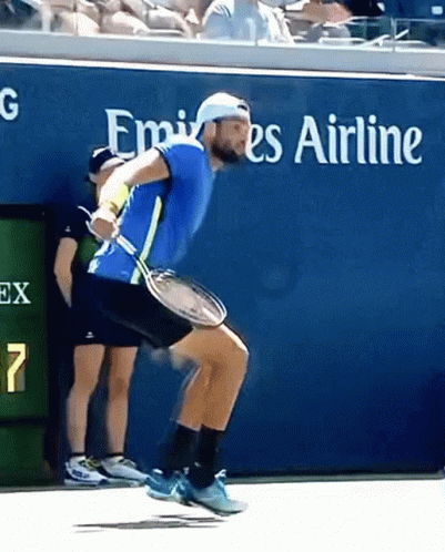 Man Holding Tennis Racket in Front of Emirates Sign