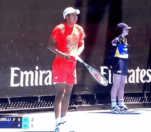 Man Holding Tennis Racquet in Front of Emirates Ad
