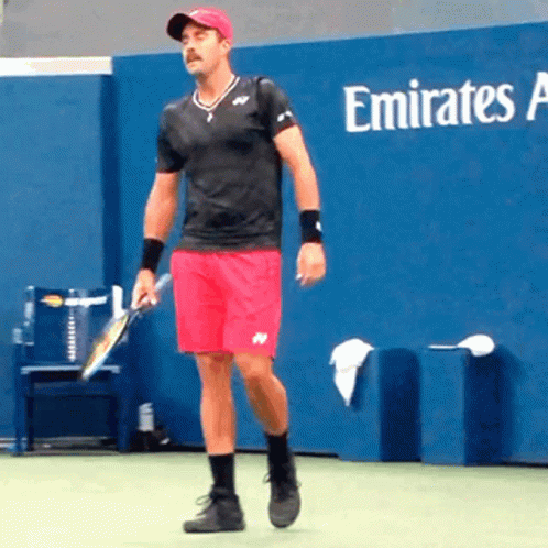 Man Holding Tennis Racquet in Front of Emirates Advertisement