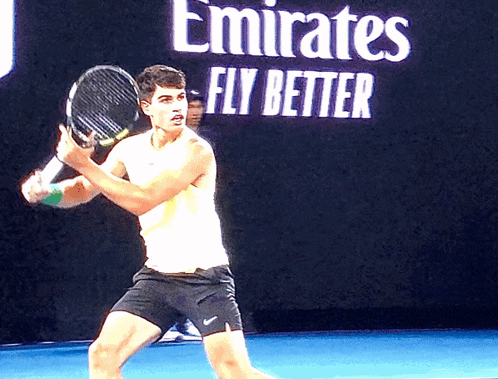 Man Holding Tennis Racquet in Front of Emirates Fly Better Sign