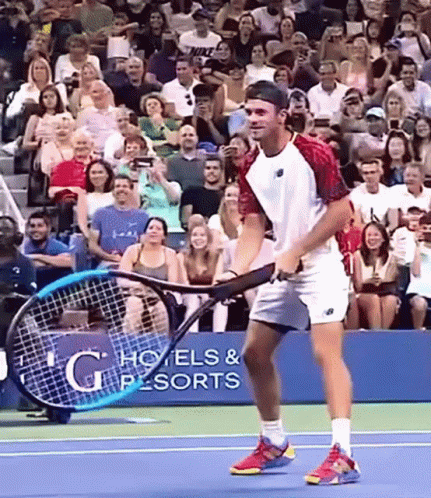 Man Holding Tennis Racquet in Front of G Hotels & Resorts Sign
