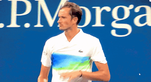 Man Holding Tennis Racquet In Front Of J.P. Org Sign GIF
