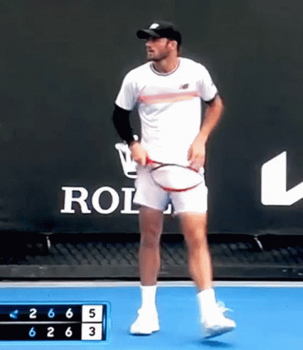 Man Holding Tennis Racquet in Front of Rolex Sign