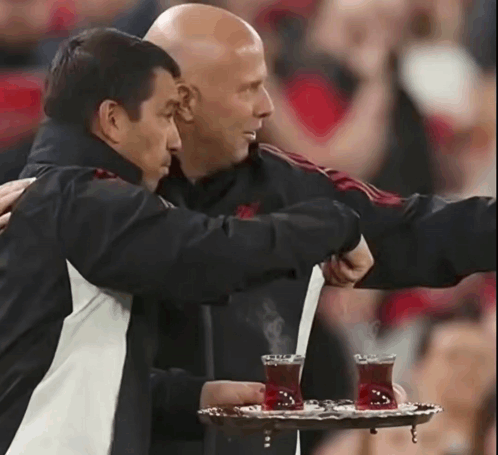 Man Holding Tray of Tea Hugged by Another