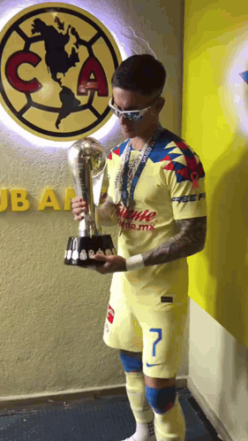 Man Holding Trophy in Front of Club America Wall