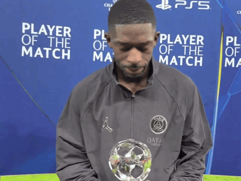 Man Holding Trophy in Front of Player of the Match Sign