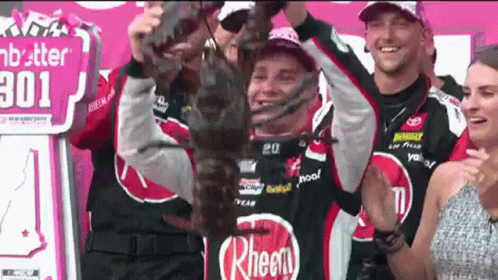 Man Holding Trophy in Front of Rheen Sign