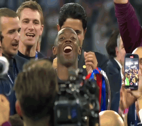 Man Holding Trophy Laughing in Front of Group