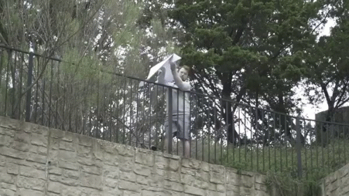 Man Holding Umbrella on Stone Wall