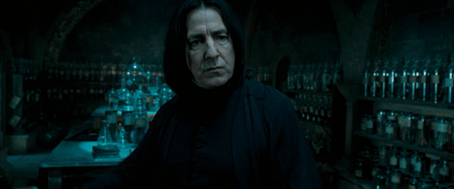 Man Holding Wand In Dark Room With Bottles GIF