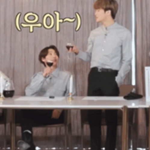 Man Holding Wine and Another Man at Table