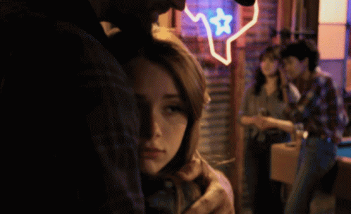 Man Hugging Woman In Front Of Texas Neon Sign GIF