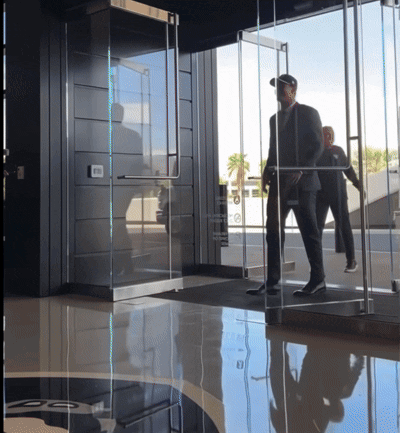 Man In A Suit Walks Through Emergency Exit Glass Door GIF