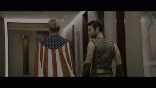 Man in American Flag Cape Next to Superhero