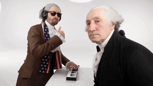 Man In American Flag Scarf Playing Piano Next To Man In Suit GIF